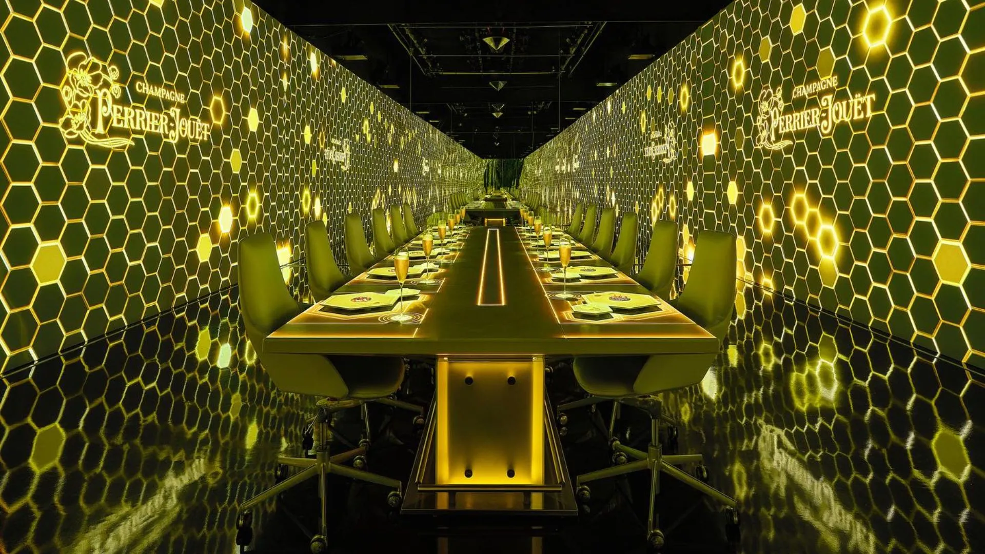 Modern luxury dining room with a long glowing table and golden honeycomb walls.