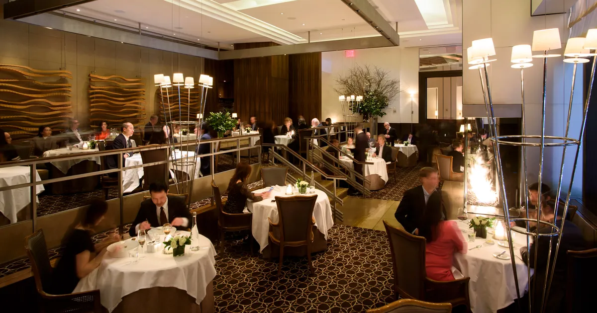 Multi-level upscale restaurant dining room with tall decorative lamp posts and round tables.