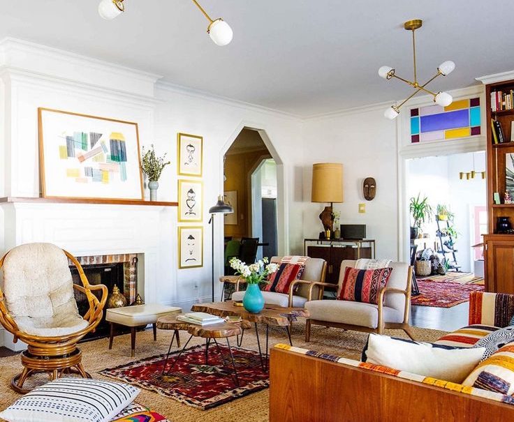 Eclectic boho living room with a white fireplace, wooden furniture, brass light fixtures, and colorful patterned textiles. mid-century modern